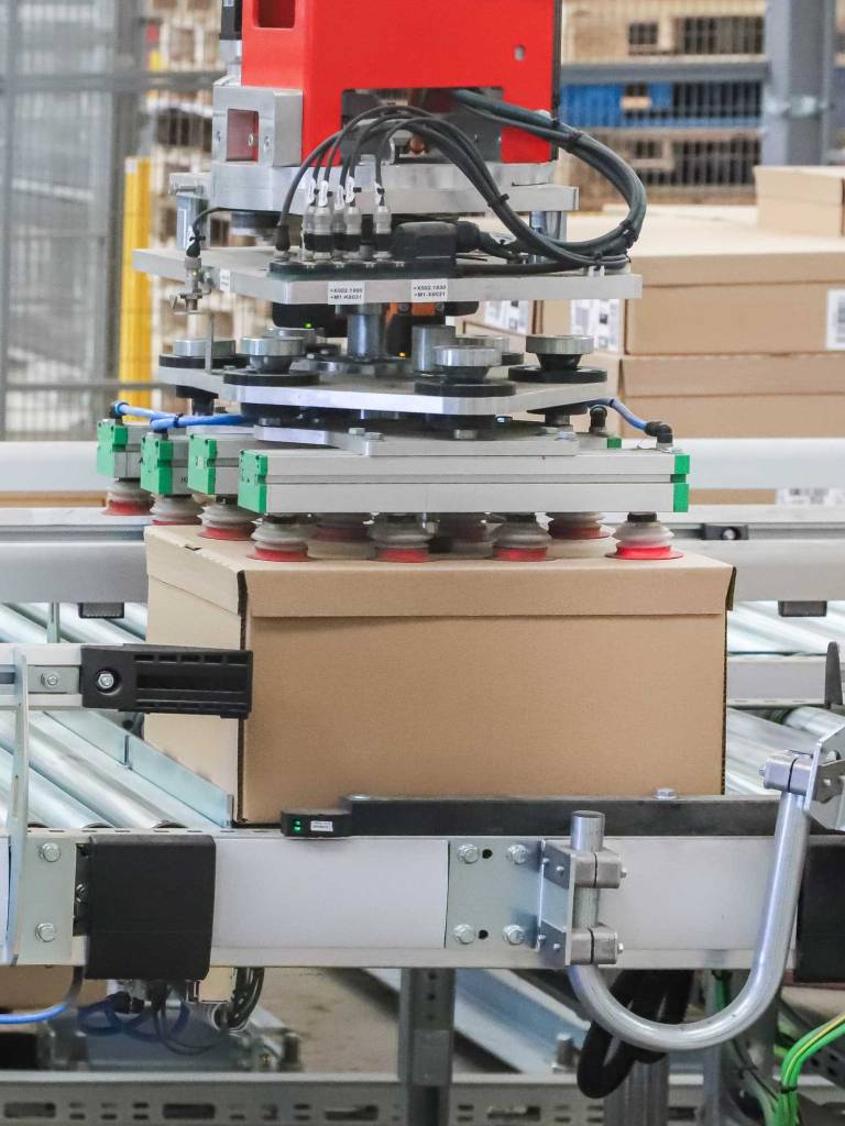automated box package handling using vacuum suction on roller conveyor