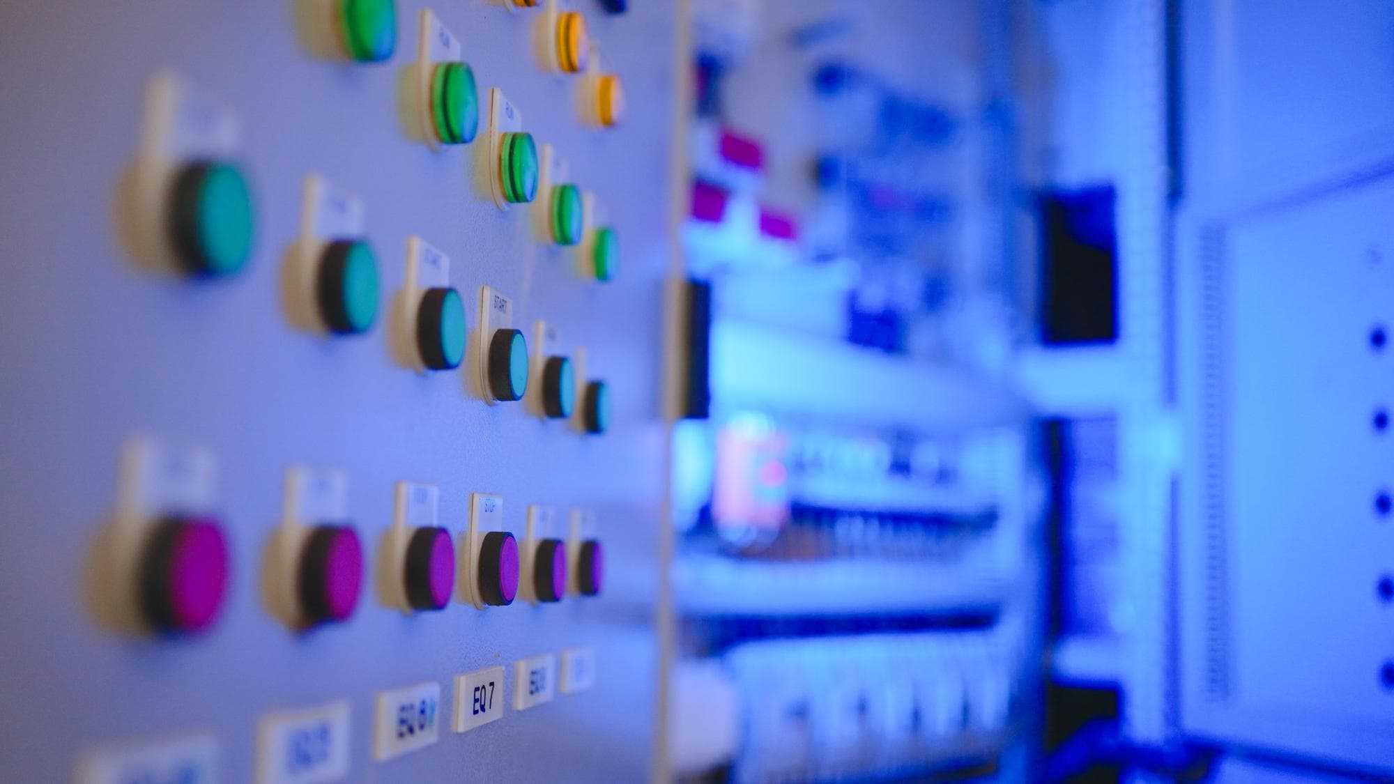 industrial control panel with illuminated push buttons and labeled operator controls inside a modern manufacturing facility