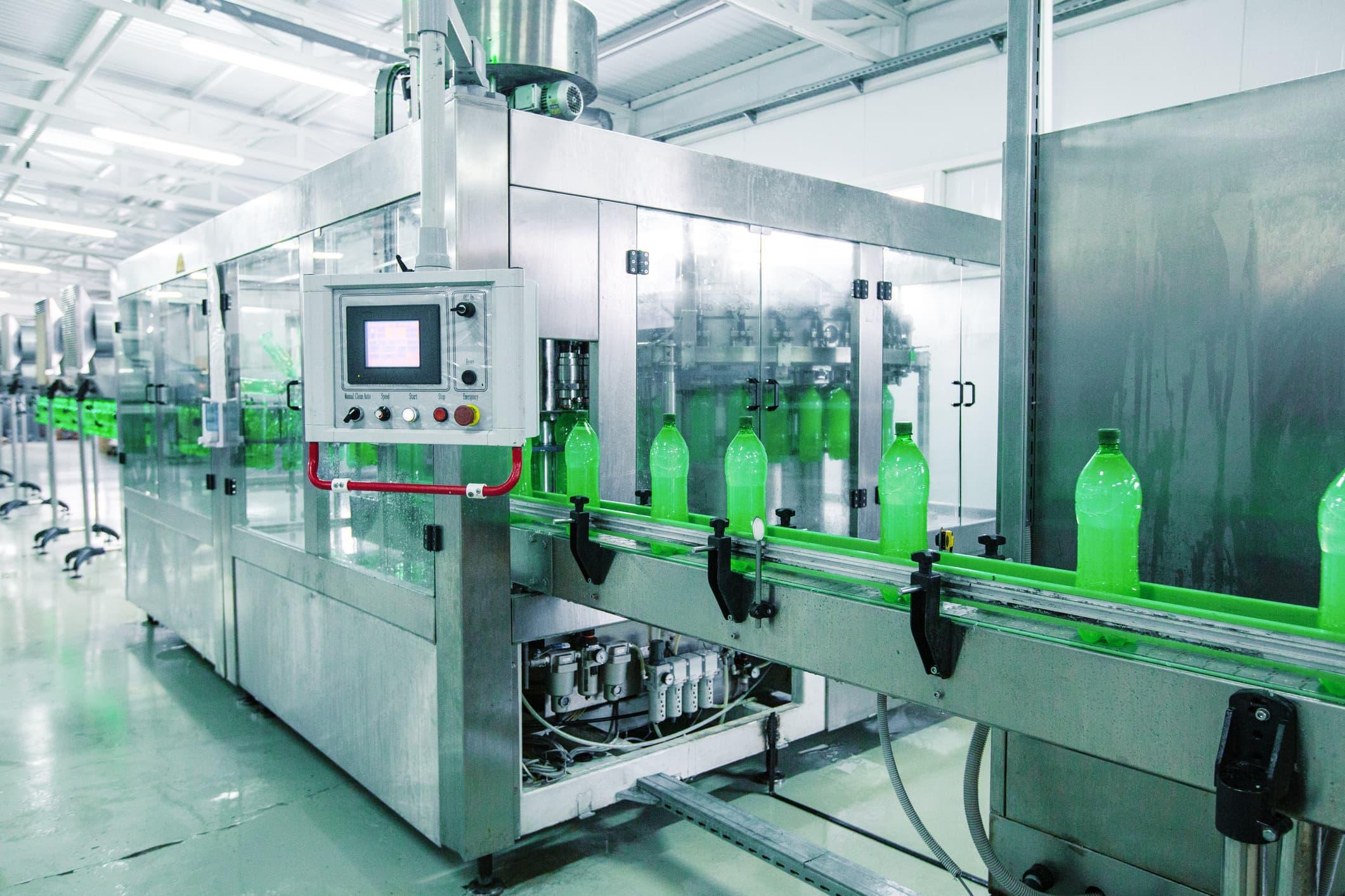 automated beverage bottling line with green bottles moving through a controlled filling and processing system