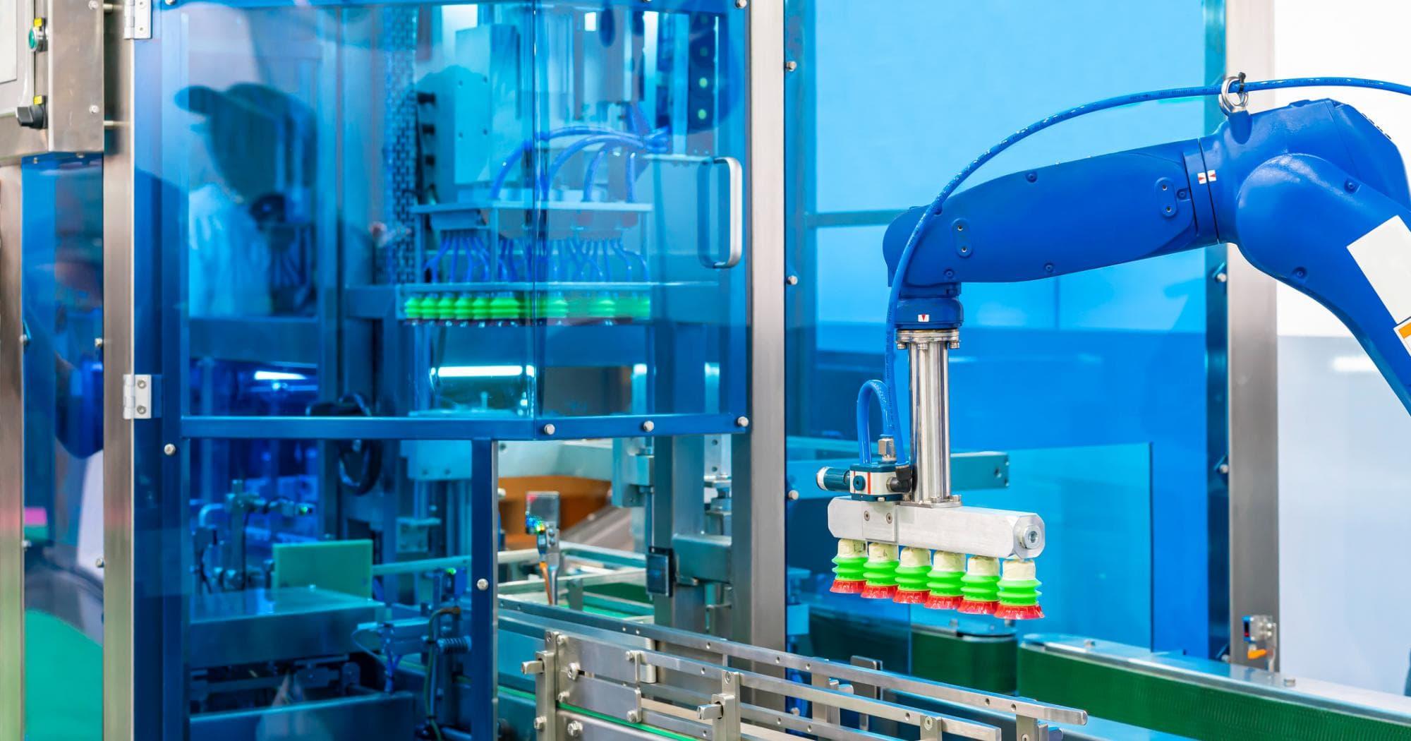 automated robotic arm with suction gripper moving bottles along a conveyor inside a protected industrial production cell