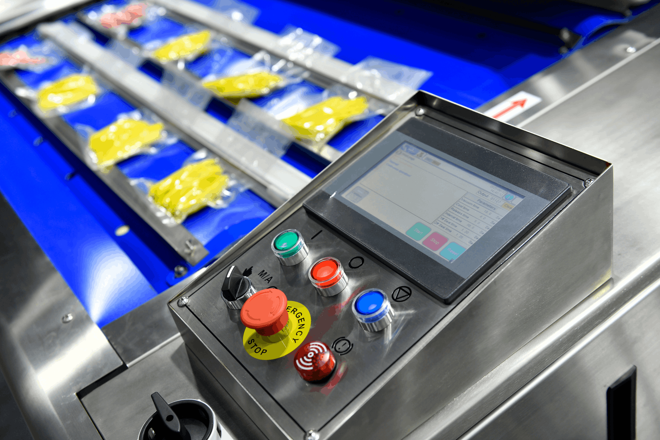 close‑up of a food packaging machine sealing pouches while an operator panel shows start and stop controls, illustrating how disconnected equipment like legacy fillers and OEM packers create manual checks and slow changeovers, and how integrated plc, hmi, scada, mes, and erp systems give teams a single view of the line to improve flow and reduce disruptions