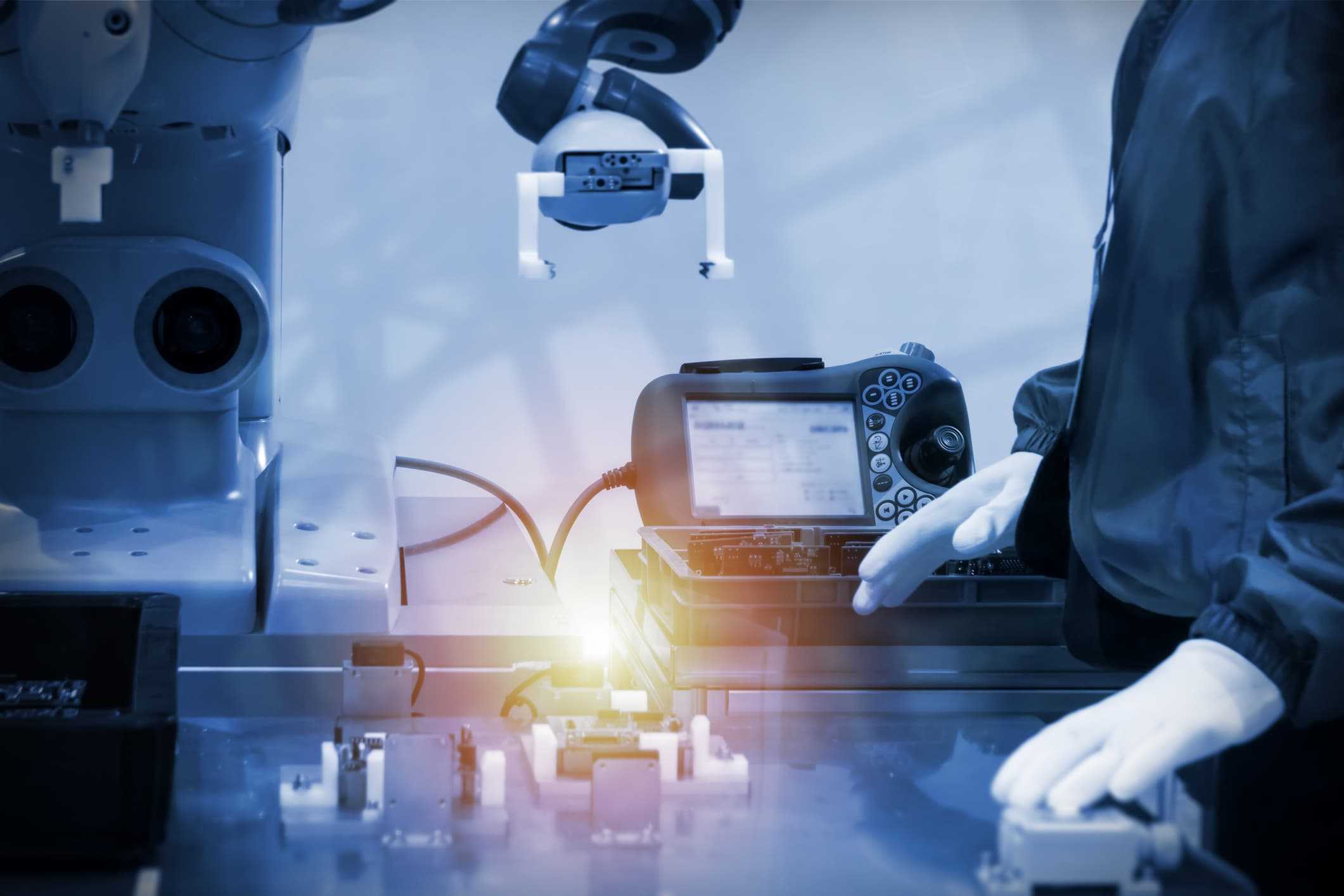 robotic arm performing precision tasks while a technician uses a handheld interface to guide adaptive, human‑centric production workflows