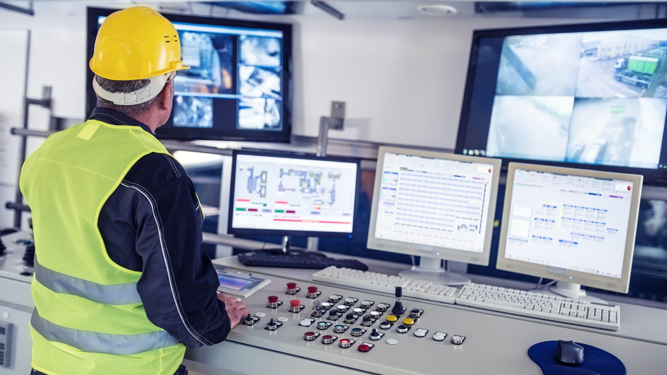 operator in a modern facility monitoring production conditions from a multi-screen control station